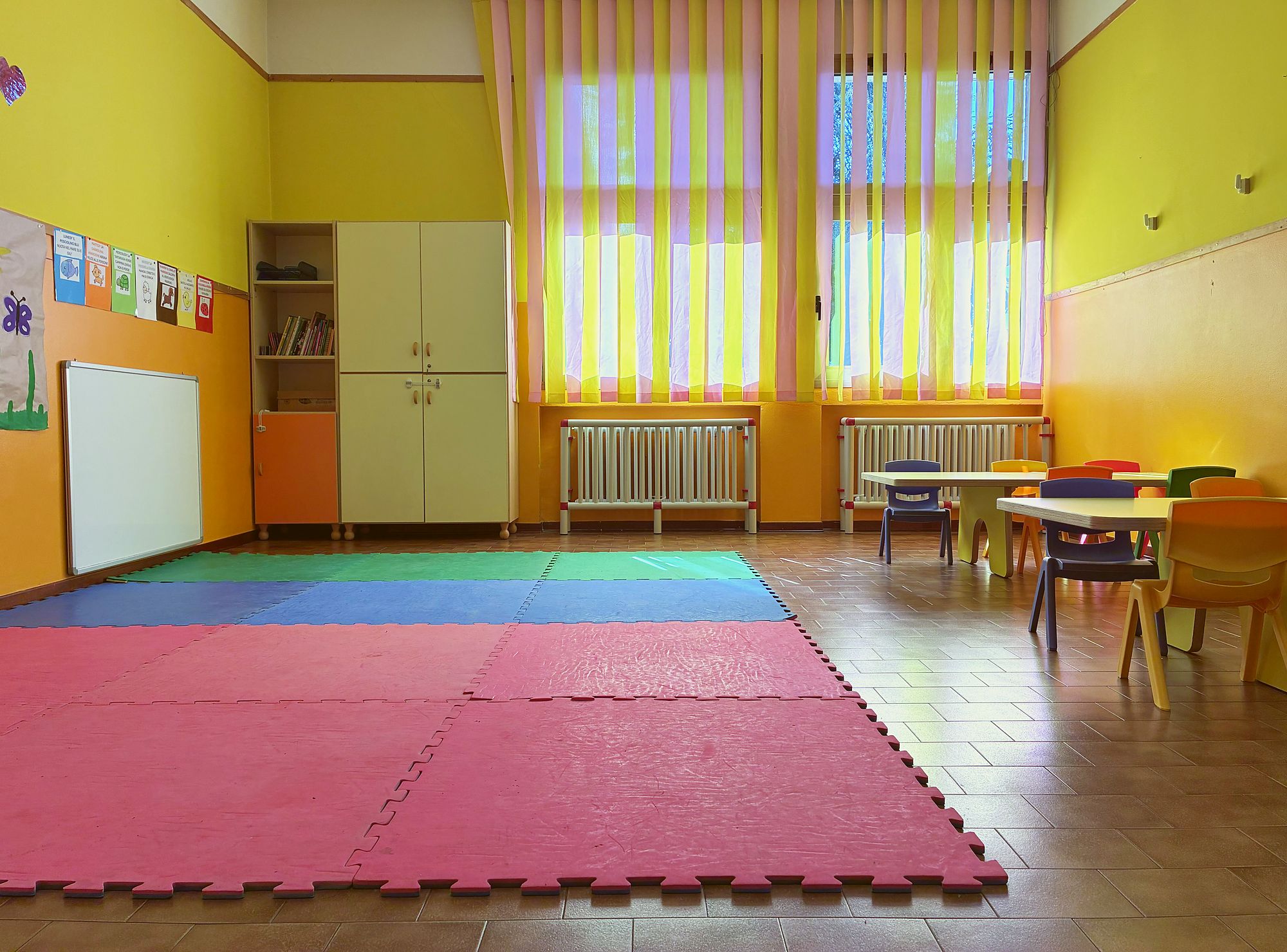 Aula della sezione primavera con tappeti morbidi e tavoli colorati